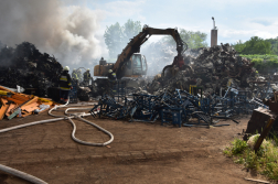 Tűzoltók oltják a felhalmozott hulladékot munkagép segítségével
