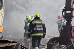 Tűzoltók oltják a felhalmozott hulladékot munkagép segítségével